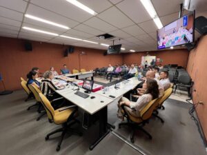 Reunião pública na Planurb com participantes sentados e mesa de autoridades ao fundo