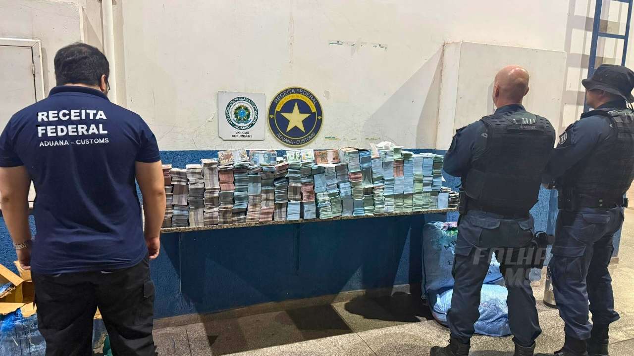Agentes da Receita Federal e Polícia Militar fiscalizando notas falsas de reais e dólares apreendidas em táxi boliviano no Posto Esdras, fronteira com Corumbá.