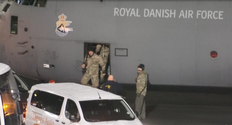 Avião militar dinamarquês pousando em pista de aeroporto na Groenlândia, com soldados desembarcando.