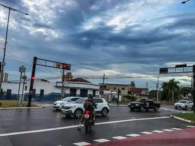 Céu parcialmente nublado sobre uma cidade em Mato Grosso do Sul, com chuva fraca e nuvens escuras indicando temporais isolados se aproximando.