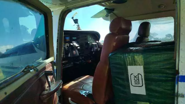 Avião monomotor boliviano abandonado em campo de terra em Porto Murtinho, MS, com equipe da Polícia Federal ao fundo.