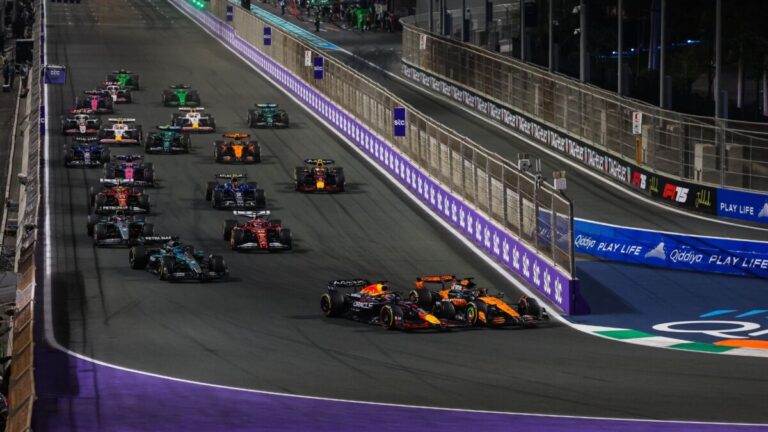 Carro de Fórmula 1 em alta velocidade exibindo tecnologia aerodinâmica avançada em uma pista de corrida ao pôr do sol.