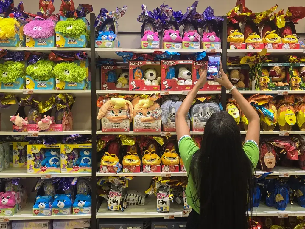 Carrinho de compras com poucos itens de Páscoa em supermercado, simbolizando a queda nas vendas devido ao endividamento em MS.