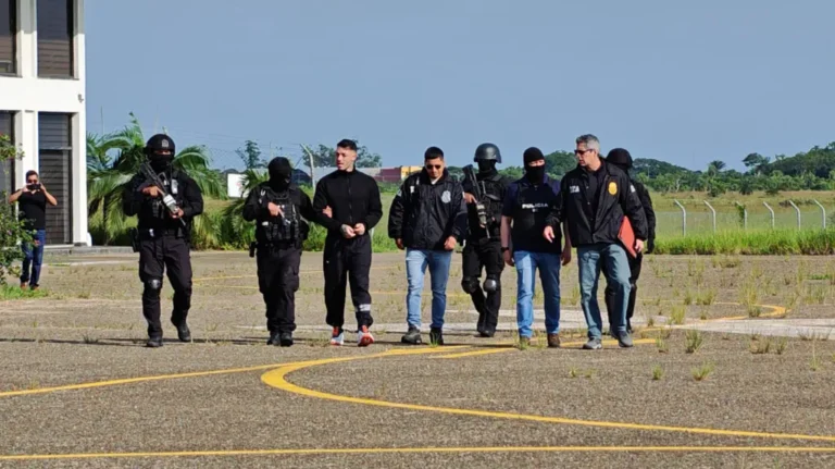 Sebastián Marset sendo detido por policiais em megaoperação na Bolívia, com viaturas e agentes da DEA ao fundo.
