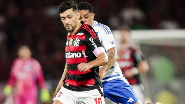 Campo de futebol iluminado por holofotes, pronto para receber uma partida.