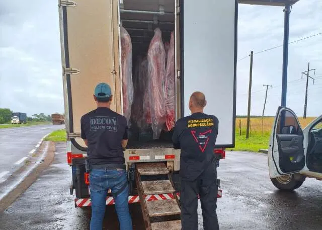 Agentes de fiscalização e policiais inspecionando carne suína apreendida em entreposto clandestino em Dourados.