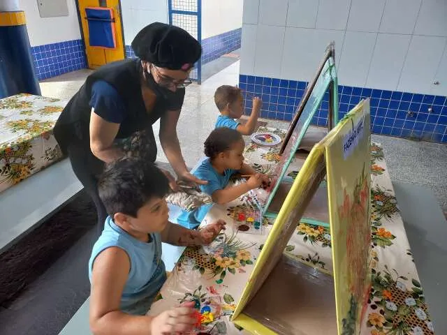 Assistentes de educação infantil interagindo com crianças em sala de aula