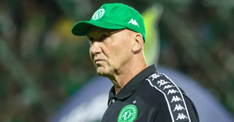 Escudo da Chapecoense em campo de futebol com atmosfera sombria.