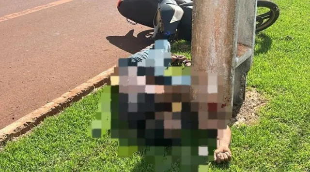 Local do crime na MS-165 com motocicleta caída, equipe do Samu e isolamento policial ao entardecer.