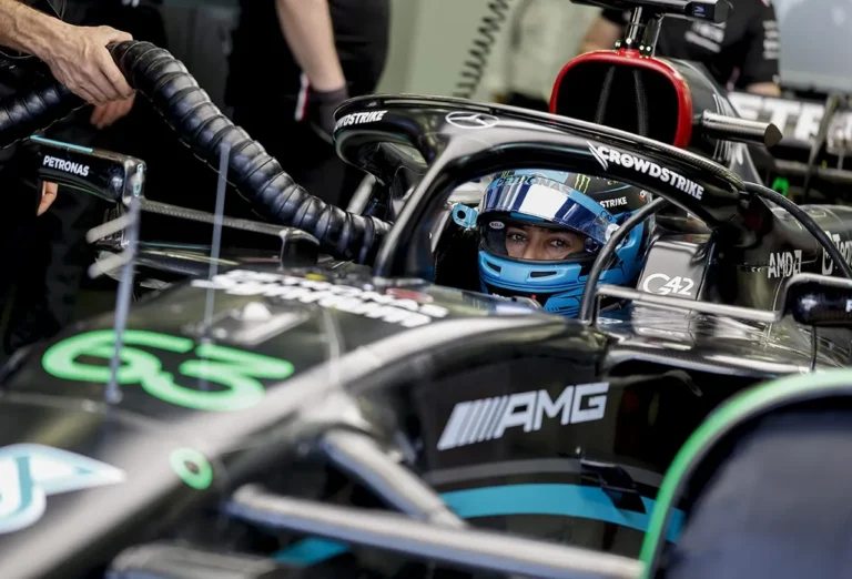 Carro de Fórmula 1 no box com equipe técnica próxima ao tanque de combustível
