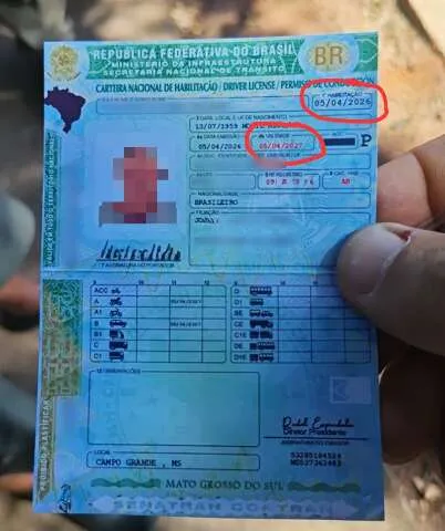 Homem idoso sendo abordado por policial de trânsito que examina sua CNH