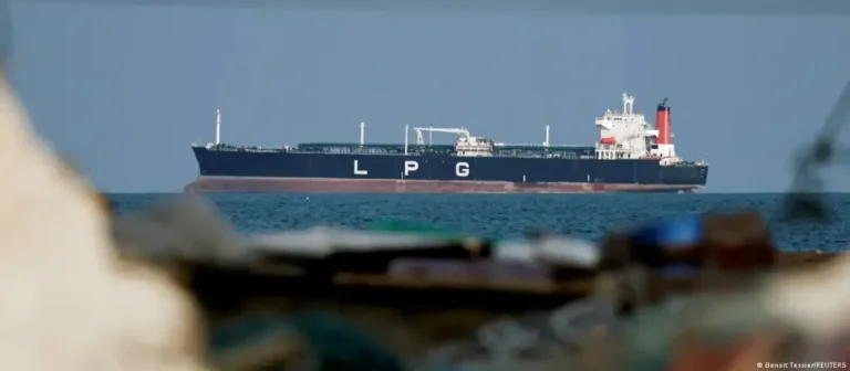 Navio petroleiro no Estreito de Ormuz com navios de guerra ao fundo