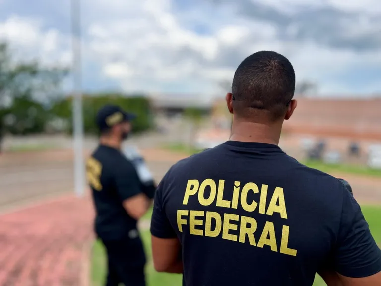 Agentes da Polícia Federal em Sete Quedas, MS, inspecionando cigarros contrabandeados e provas apreendidas.