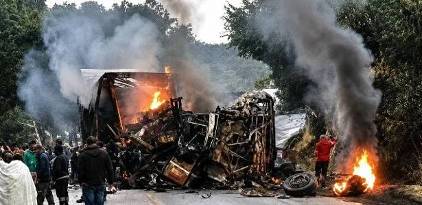 Cena do acidente entre ônibus e carreta carbonizados com equipes de resgate e ambulâncias na via