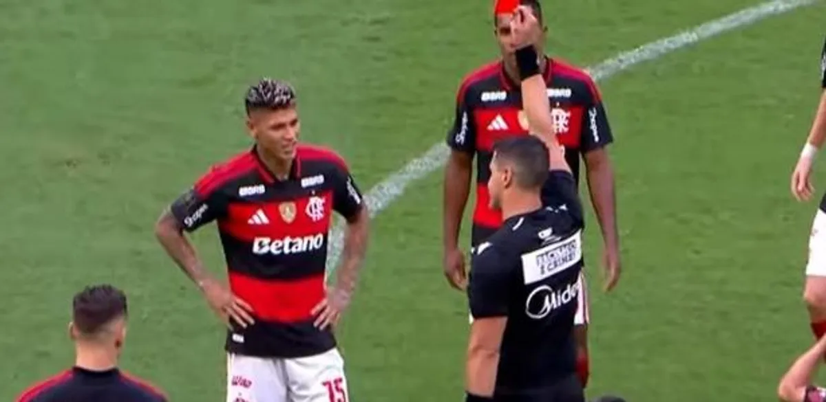 Jogador do Flamengo deixando o campo após expulsão enquanto árbitro segura cartão vermelho