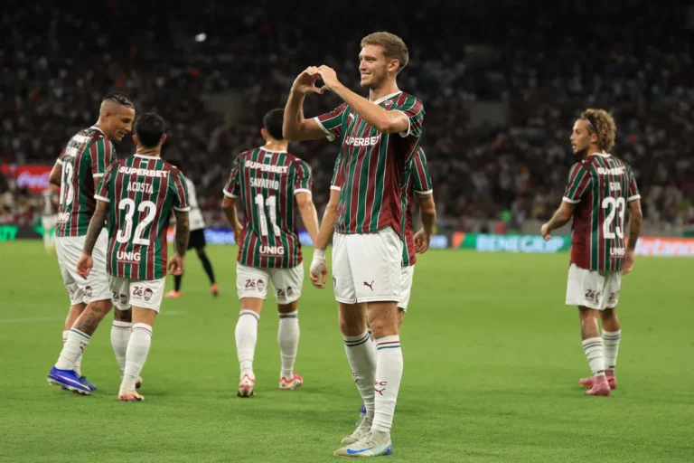Estádio de futebol com bandeiras do Fluminense e do Vasco nas arquibancadas antes de jogo