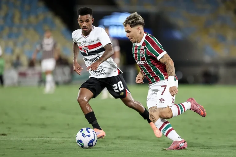Estádio do Maracanã iluminado à noite com torcida e jogadores em campo antes de Fluminense e São Paulo