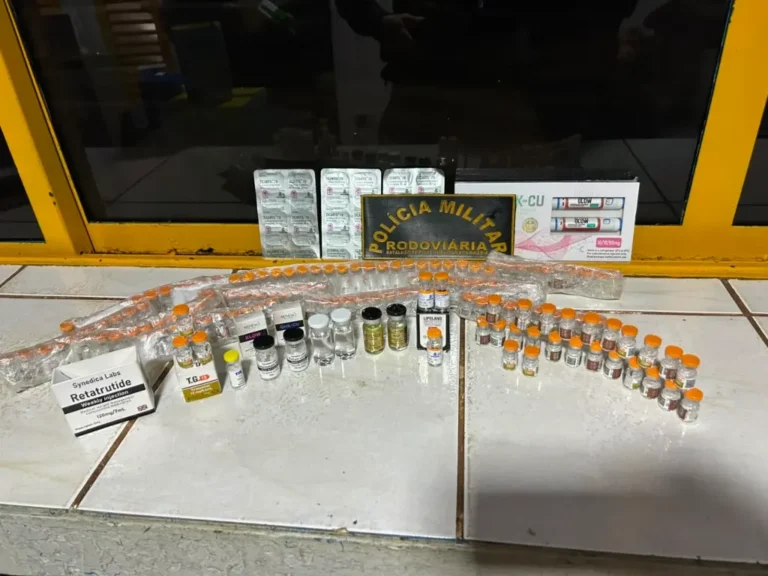 Abordagem noturna na MS-240 com policiais inspecionando frascos de medicamentos apreendidos junto a um Fiat Grand Siena.