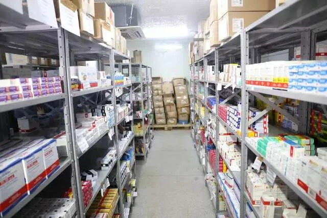 Armazém farmacêutico com trabalhador escaneando caixas e van de entrega ao fundo