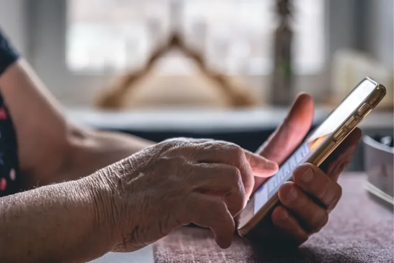 Idosa preocupada olhando smartphone após golpe por vídeo chamada no WhatsApp