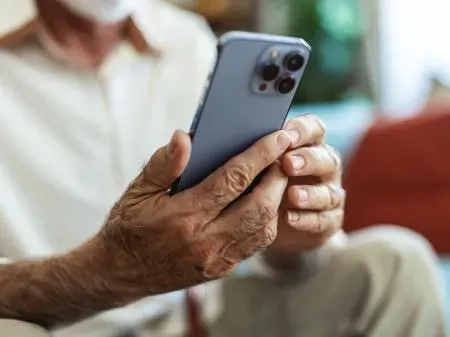 Pessoa idosa usando smartphone em casa, simbolizando aumento do acesso à internet