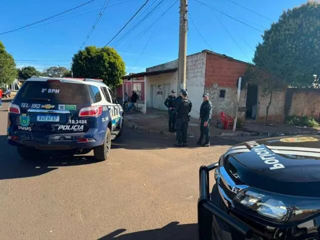 Calçada de bairro com fitas de isolamento e motocicleta em fuga em cena de crime em Nova Andradina