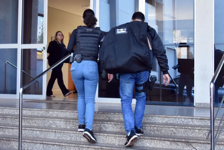 Fórum de Dourados com viatura policial e documentos representando operação judicial