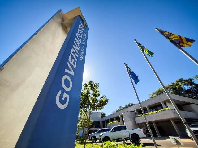 Fachada do governo estadual com gráficos mostrando redução da dívida e documentos com selo PROPAG