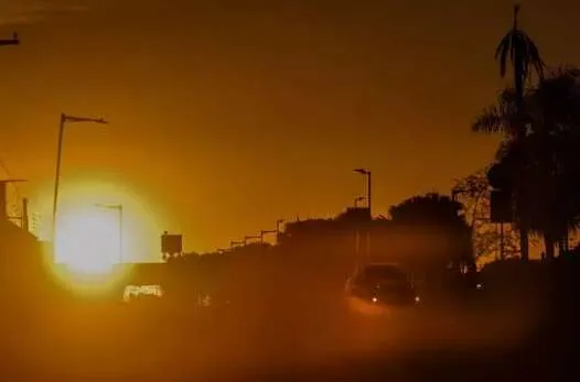 Paisagem seca e ensolarada em Mato Grosso do Sul com vegetação ressecada e leve fumaça, indicando risco de incêndio