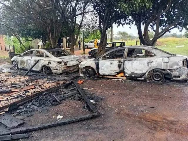Posto policial de madeira queimado na Colônia Naranjito com veículos carbonizados e peritos no local à noite