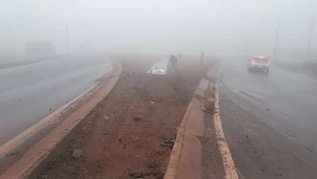 Trecho da BR-463 com neblina densa e motocicleta caída próxima a poça de água