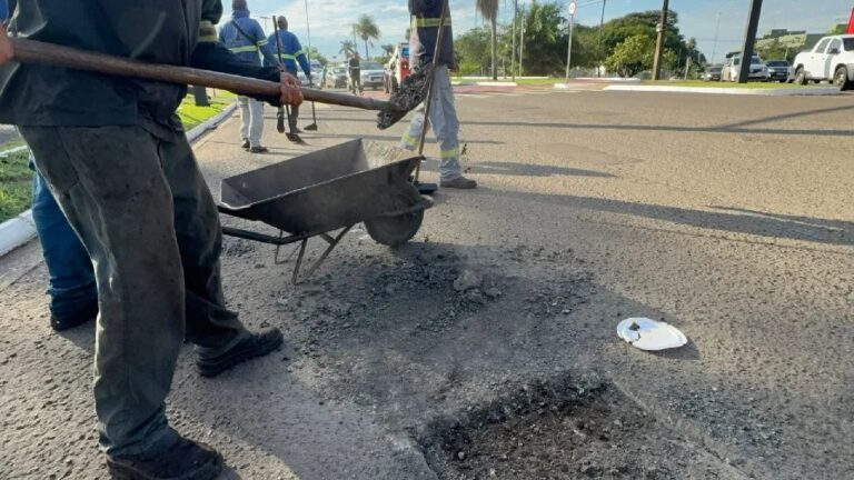 Equipes municipais reparando buracos na rua com caminhões e máquinas em Vila Moreninha III