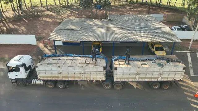 Carreta apreendida na MS-164 com policiais vistoriando caixas de cigarros contrabandeados