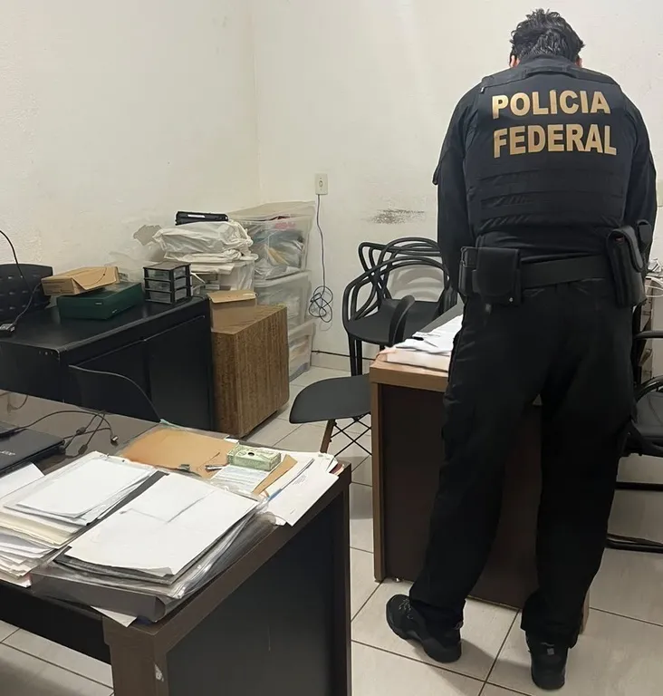 Agentes da Polícia Federal em operação com documentos e ícones de criptomoedas, ilustrando investigação sobre lavagem de dinheiro ligada a apostas ilegais.