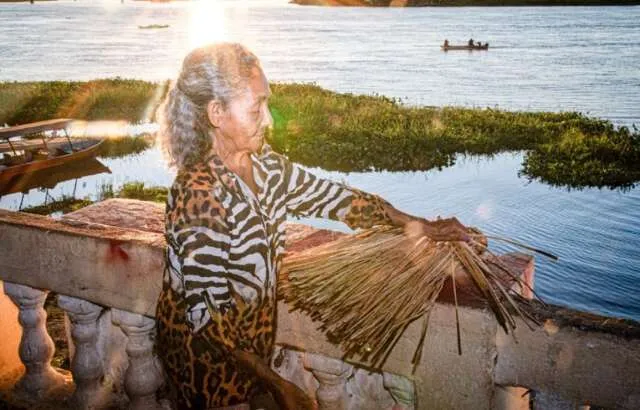 Representantes Terena e Guató na margem do Pantanal com embarcação de dragagem ao fundo