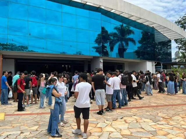 Estudantes diverse em frente a instituição de ensino com laptop mostrando 'Prouni 2026'