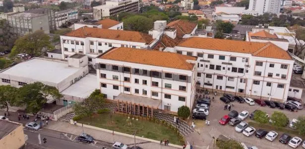 Profissionais de saúde atendendo recém-nascido enrolado em cobertor em corredor de hospital