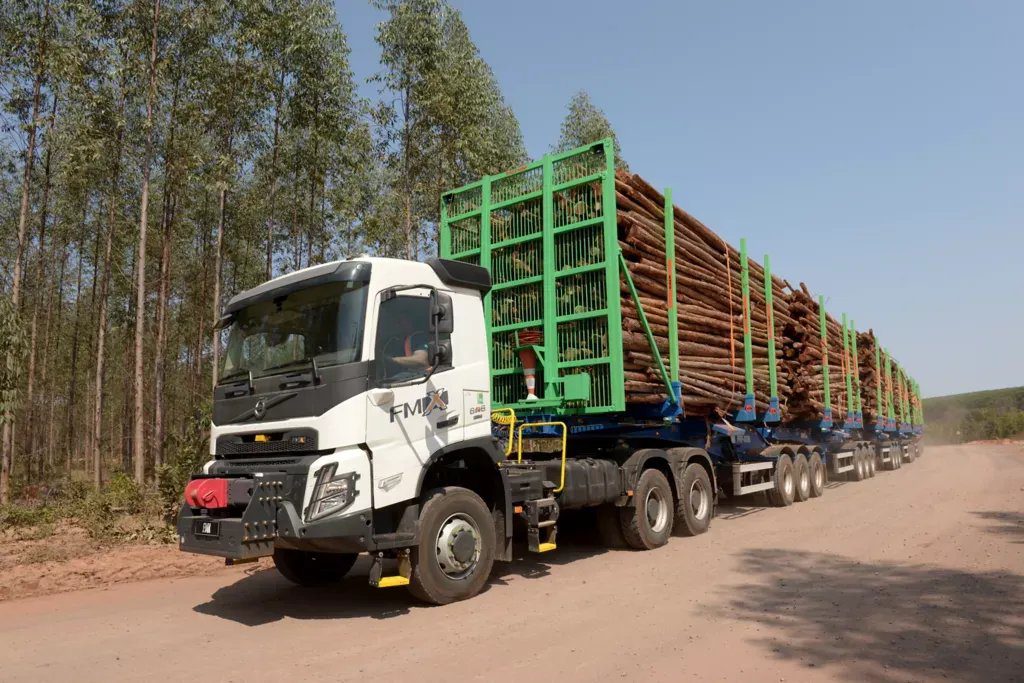 Hexatrens da Suzano em estrada não pavimentada de MS com identificação 'Veículo em teste' e equipe técnica ao lado