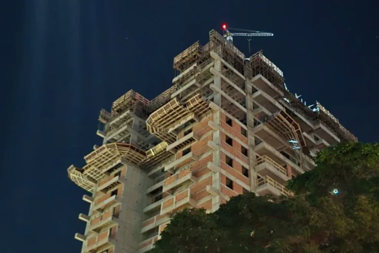 Obra em construção isolada com fita de segurança, viatura dos bombeiros e equipe de perícia no local