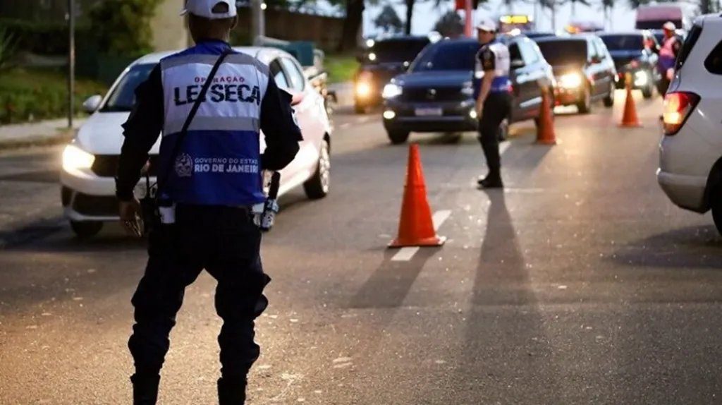 Agente de trânsito aplicando teste de saliva em um motorista durante blitz
