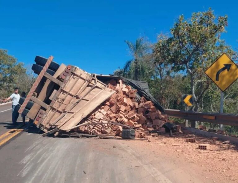 Caminhão tombado na BR-262 com tijolos espalhados na pista.