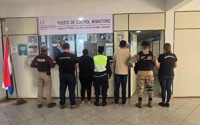 Casal algemado sendo escoltado por policiais federais na fronteira