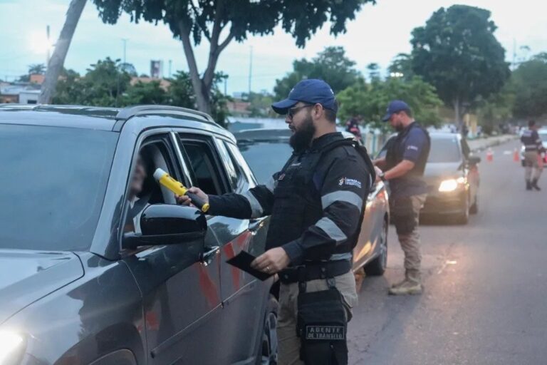 Agente de trânsito realiza pré-teste de alcoolemia em motorista durante blitz noturna