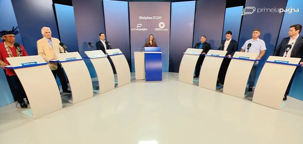 Palco de debate político vazio com cadeiras e câmeras de TV