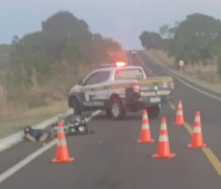 Carro e moto em rodovia com viaturas policiais ao fundo, em MS.