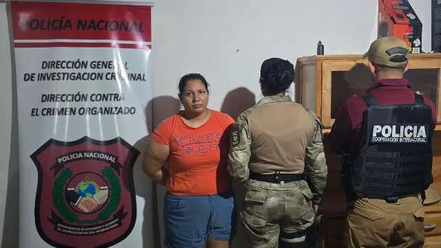 Mulher segurando um bebê enquanto é detida por policiais em local noturno