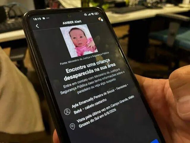 Policial segura um homem algemado durante prisão em bairro de Campo Grande
