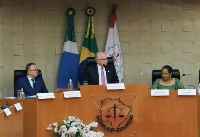 Mão segurando balança da justiça sobre mapa da fronteira entre Brasil, Paraguai e Bolívia