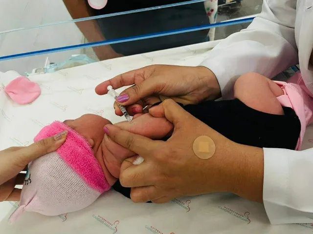 Bebê recebendo vacina contra meningite aplicado por profissional de saúde