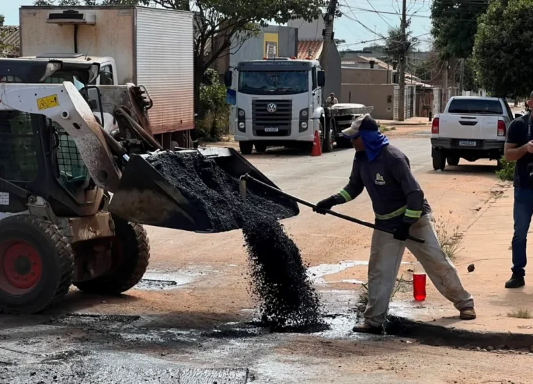 Equipe com maquinário aplicando asfalto em reparo tapa-buraco em via urbana de Campo Grande
